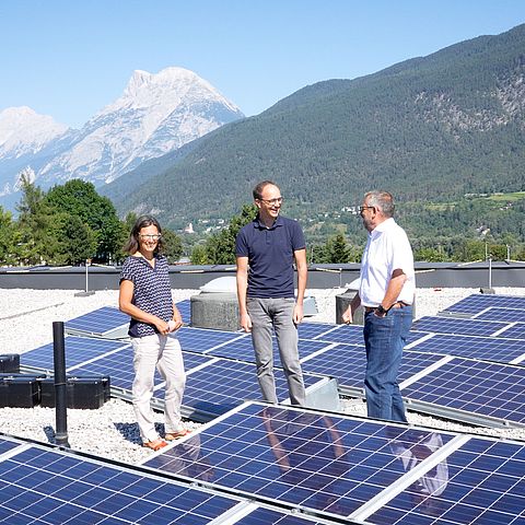 Drei Personen auf einem Dach mit PV-Anlagen