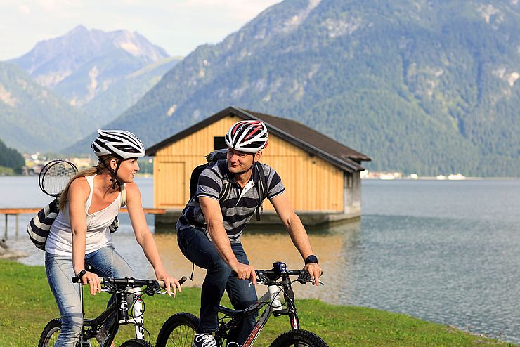 Eine Frau und ein Mann fahren mit ihren Rädern entlang des Achensees