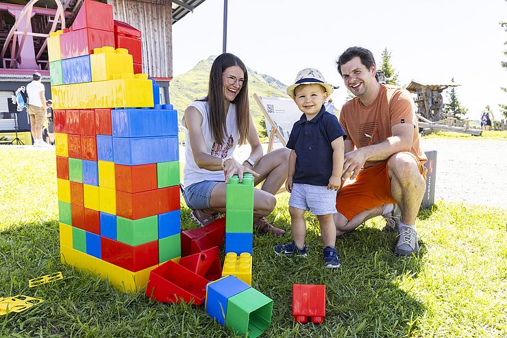 zwei Erwachsene und ein Kleinkind mit Riesen-Lego-Bausteinelstation