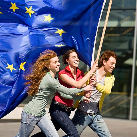 Drei junge Personen tragen die EU-Fahne