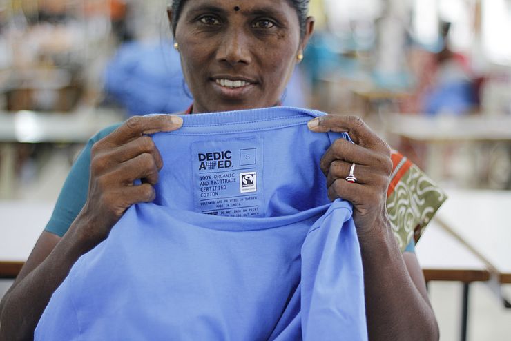 Frau, die ein blaues Fairtrade T-Shirt in den Händen hält