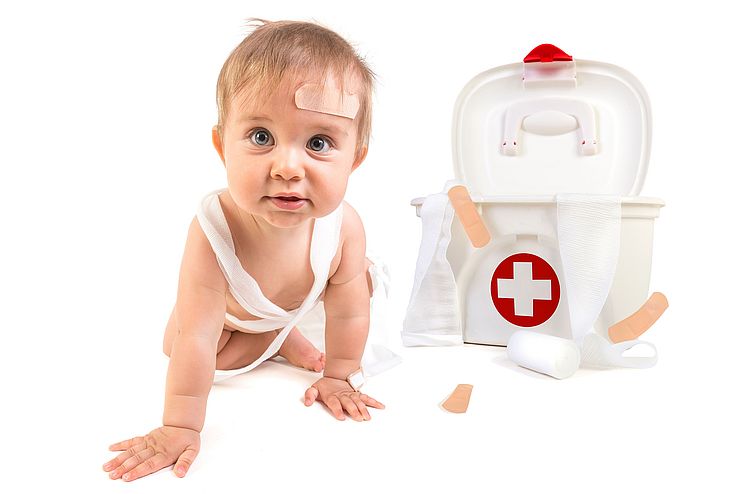  Baby krabbelt neben Erste-Hilfe-Koffer