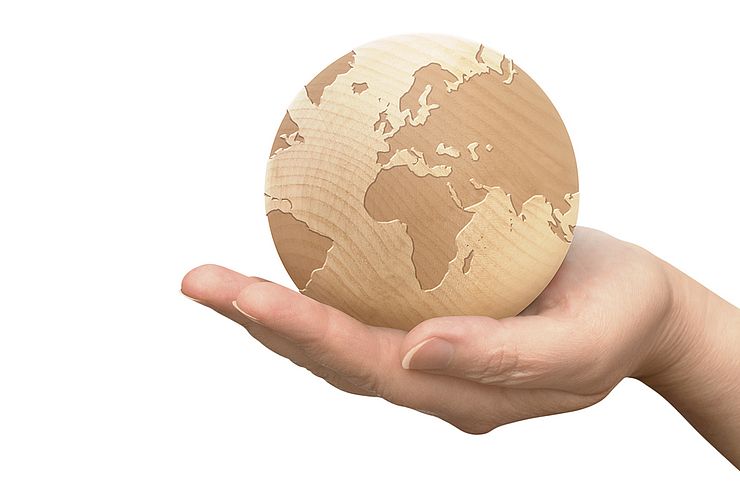 Zirbenholzkugel mit Globus-Belaserung gehalten von einer Hand