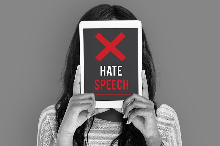 Jugendliche hält Schild mit der Aufschrift "Hate Speech"