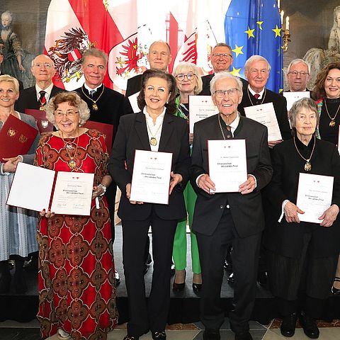 13 Personen stehen im Riesensaal der Hofburg und präsentieren stolz ihre Auszeichnung "Ehrenzeichen des Landes Tirol". 