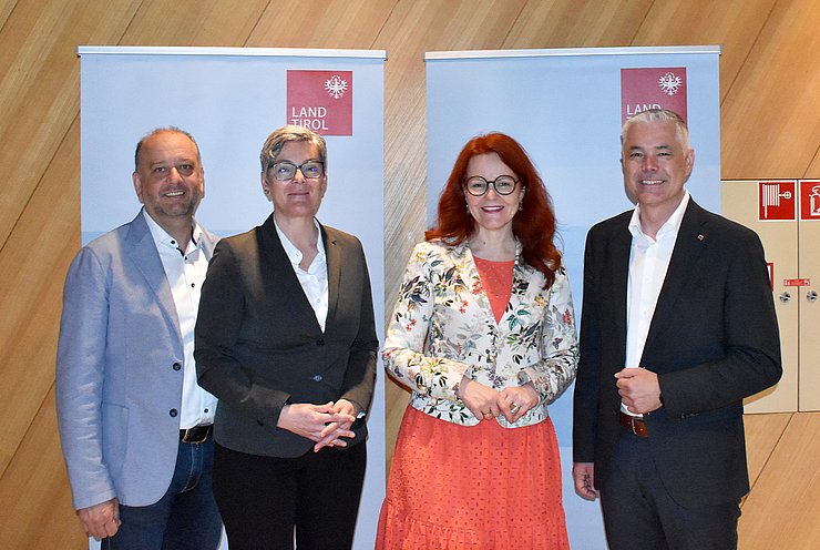 Gruppenbild von der Regionalkonferenz vor 2 blauen Aufstellern mit roten Landeslogos im Gemeinesaal in Kematen in Tirol