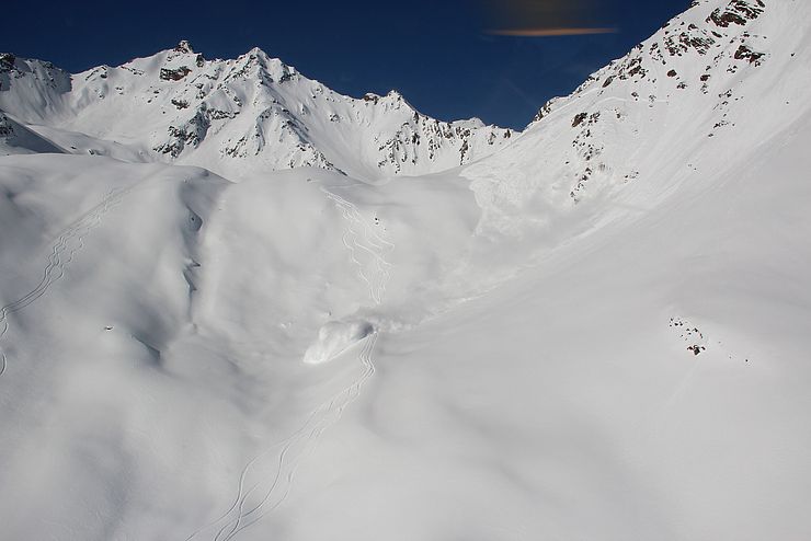 Gefährliche Schneebrettlawine während eines Abgangs südlich des Gaislachkogels in den südlichen Ötztaler Alpen - der Pfeil zeigt eine beginnende Staubentwicklung, der Kreis zwei Variantenfahrer.