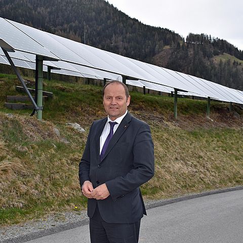LHStv Josef Geisler steht vor PV-Anlage. Tirol wechselt beim PV-Ausbau auf die Überholspur. LHStv Josef Geisler kündigt weitere Erleichterungen für gebäudenahe PV-Anlagen und kleinere Freiflächenanlagen an. Neun von zehn PV-Anlagen sind künftig anzeigen- und bewilligungsfrei. 