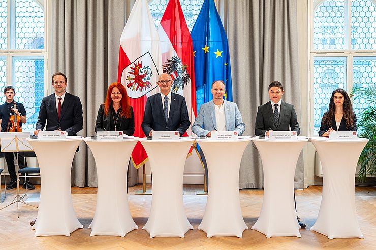 Mehrere Personen stehen hinter Stehtischen.
