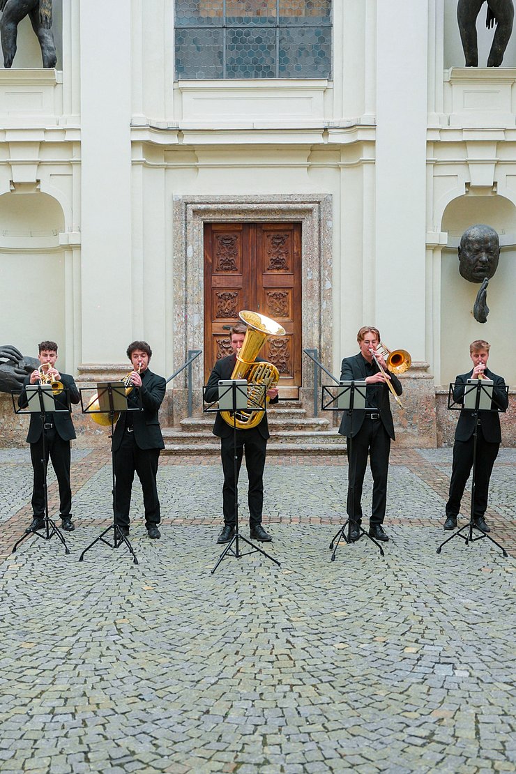 © Land Tirol/Neuner Fünf Musiker stehen vor einer Kapelle und spielen.