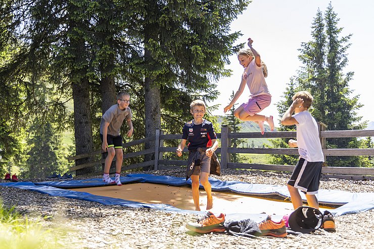 vier hüpfende Kinder auf einem Trampolin