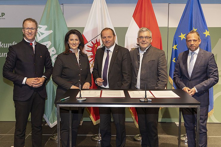 Gruppenbild der LandesrätInnen vor Fahnen, auf dem Tisch liegen Dokumente zur Unterzeichnung