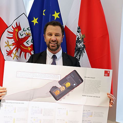 LHStv Georg Dornauer mit einem Exemplar des Tiroler Integrationskalenders 2024 in seiner Hand