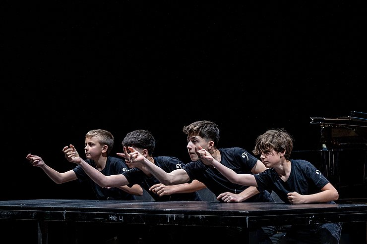 Vier Buben klopfen auf einen Tisch.