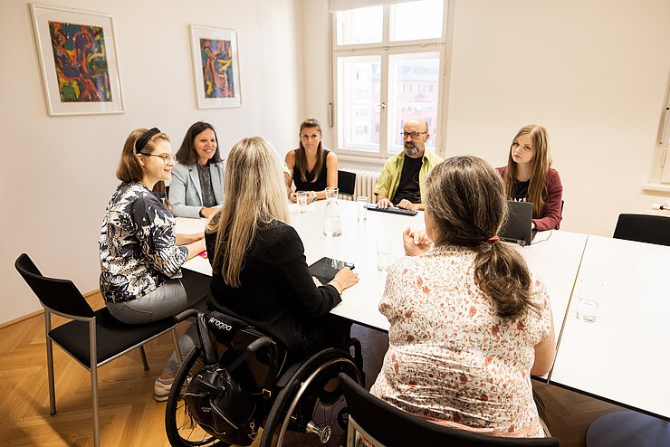 Menschen um Tisch sitzend