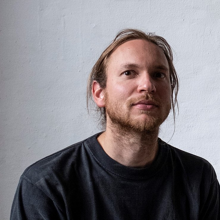 Ein Mann mit längeren Haaren blickt in die Kamera.