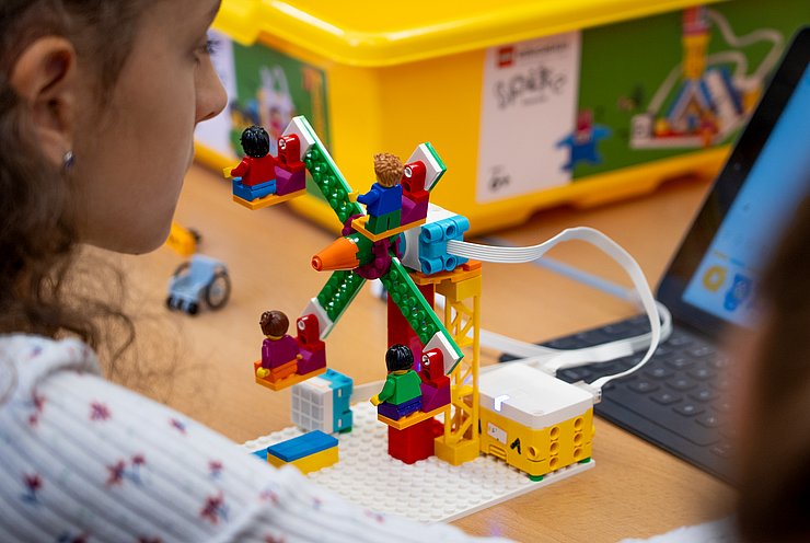 © Land Tirol/Neuner Ein Lego-Roboter vor einem Tablet.