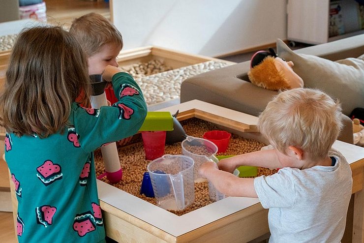 Kinder spielen in einer Kiste mit Hülsenfrüchten