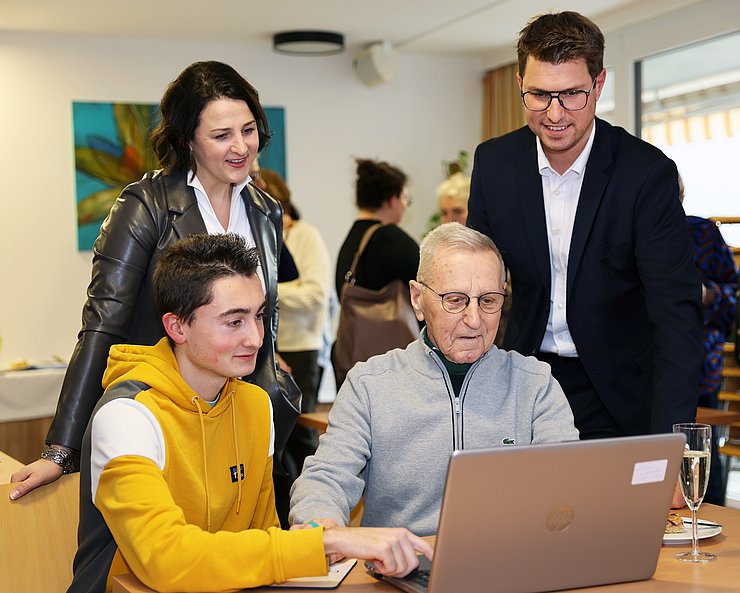 Generationenübergreifendes Lernen: Der älteste Teilnehmer Robert Braunsberger (91 Jahre) mit dem um 70 Jahre jüngeren Teammitglied Thomas Hollmann von der Computeria Telfs. LRin Astrid Mair und Bgm. Christian Härting schauen den beiden bei den Computer-Übungen über die Schultern.