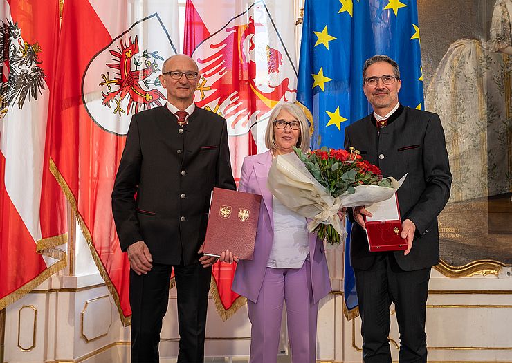 Auszeichnung für Sabine Eccel, Leiterin des VinziMarktes in Bozen, überreicht von LH Anton Mattle und LH Arno Kompatscher (re).