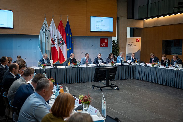 © Land Tirol/Neuner Mehrere Personen sitzen im großen Saal in einer U-Form.