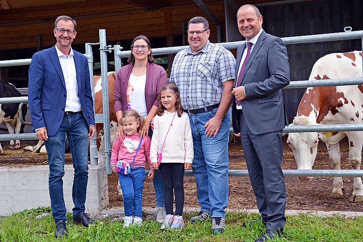 Auf dem dem Bild sind LHStv Josef Geisler (1.v.re.) und Thomas Danzl, Geschäftsführer vom Landeskulturfonds (1.v.li.) mit Georg und Manuela Kapferer sowie den zwei Töchtern Franziska (rechts) und Michaela zu sehen. Im Hintergrund sieht man den Kuhstall der Familie.