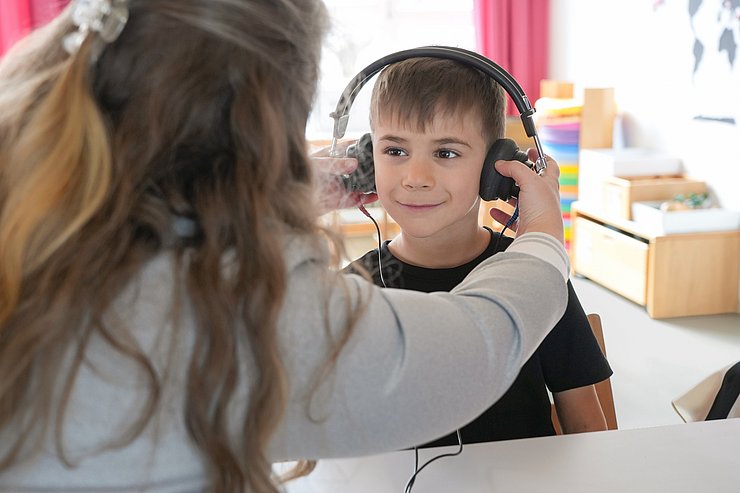 © Land Tirol/Trenker Ein Bub bekommt Kopfhörer aufgesetzt.