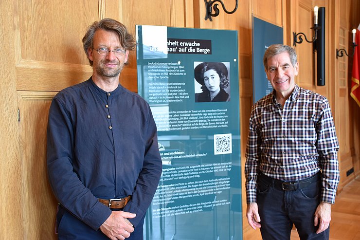 © Land Tirol/Neuner Zwei Herren stehen vor einer Ausstellungstafel.