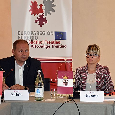 Bei einem Treffen der Europaregion sitzen an einem Tisch mit grauer Tischdecke von links LHStv Geisler und LRin Zanotelli.