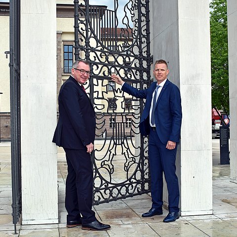 Landesrat Johannes Tratter sowie der Leiter der Liegenschaftsverwaltung des Landes Thomas Huter bei der Begutachtung des neuen Mechanismus am Wappengitter am Landhausplatz.