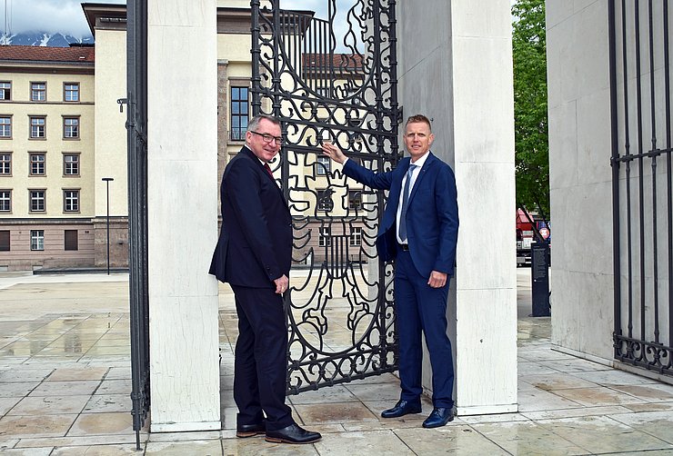 Landesrat Johannes Tratter sowie der Leiter der Liegenschaftsverwaltung des Landes Thomas Huter bei der Begutachtung des neuen Mechanismus am Wappengitter am Landhausplatz.