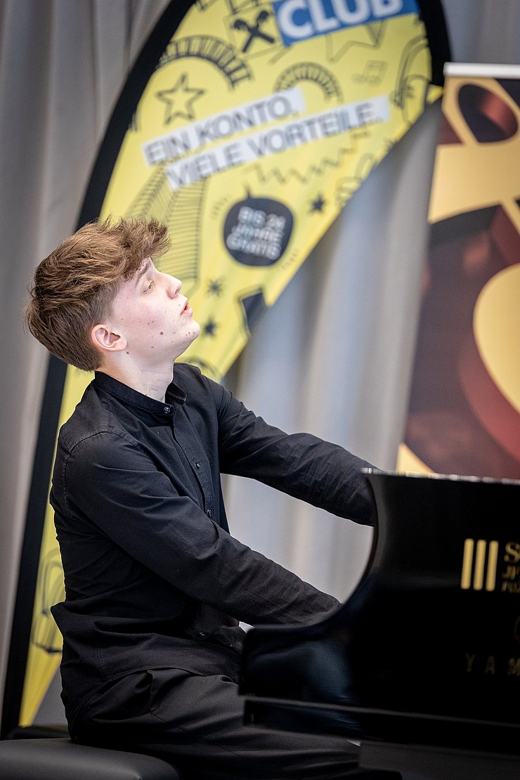 © Land Tirol/Kary Sophie Ein junger Mann spielt mit geschlossenen Augen Klavier.