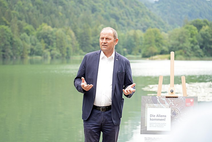 Ein Mann steht auf einem Steg am Rande eines Sees.