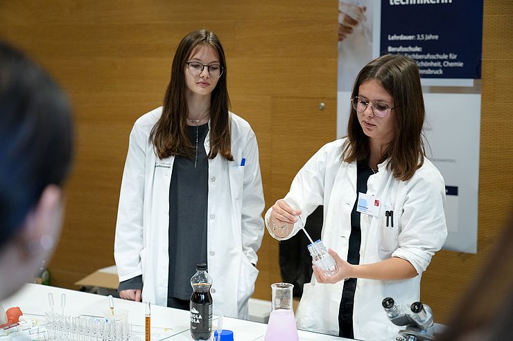 © Land Tirol/Saxl Zwei Lehrlinge aus der Labortechnik zeigen ein Experiment vor.
