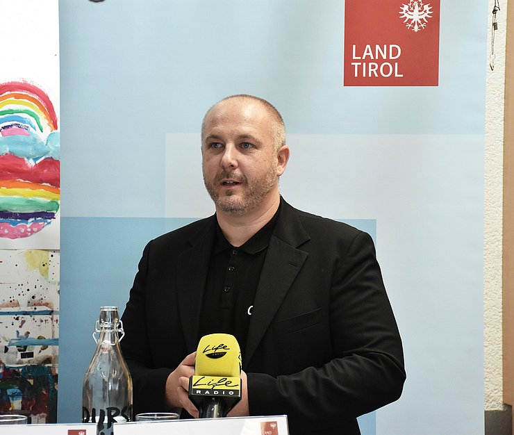 Foto von einem Mann der bei der Pressekonferenz spricht.