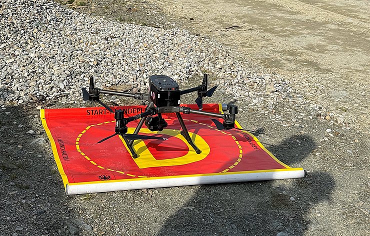 © Land Tirol/Drohnen-Einsatz-Gruppe Drohne auf rot-gelber Unterlage, die den Start- und Landeplatz markiert.