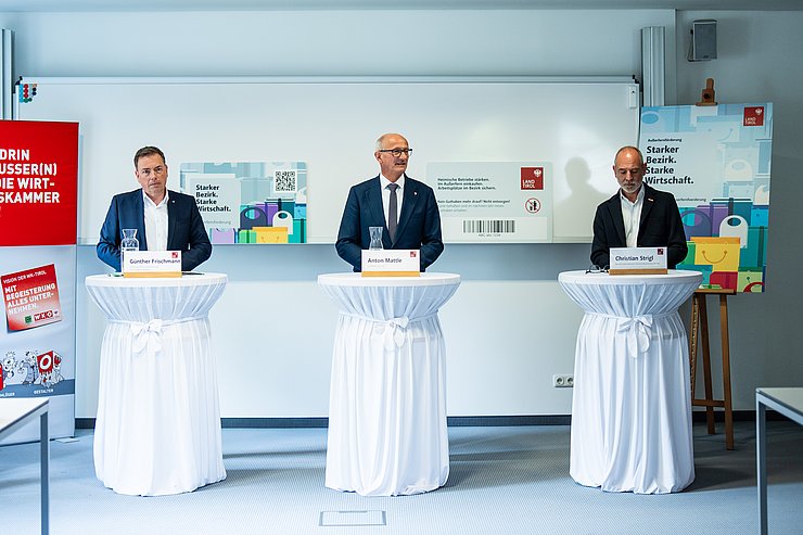 © Land Tirol/Fitsch Drei Männer im Anzug stehen an drei Stehtischen mit weißen Hussen.