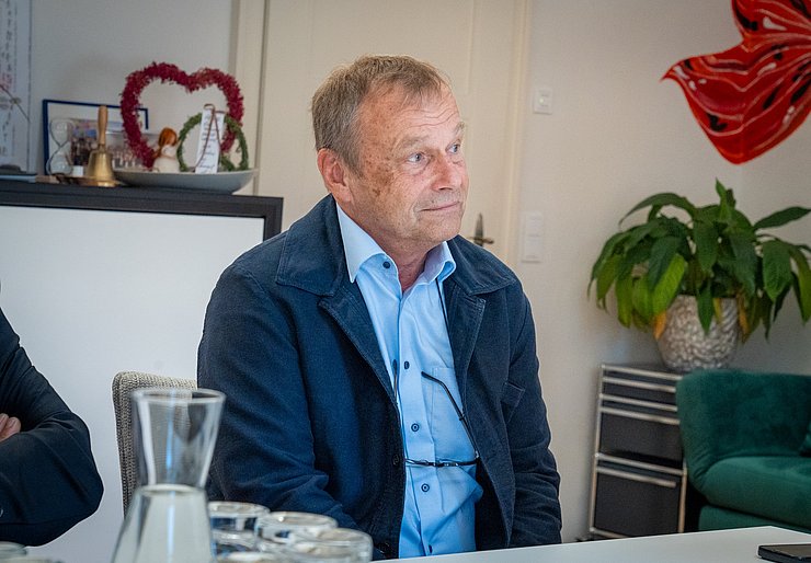 © Land Tirol/Neuner Ein Herr im blauen Hemd schaut auf eine Person außerhalb des Bildfeldes.