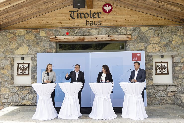 LRin Leja, LH Platter, LHStvin Felipe und Gemeideverbandpräsident Schöpf jeweils an einem Rednerpult vor dem Tiroler Haus