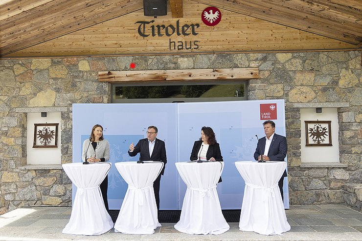 LRin Leja, LH Platter, LHStvin Felipe und Gemeideverbandpräsident Schöpf jeweils an einem Rednerpult vor dem Tiroler Haus