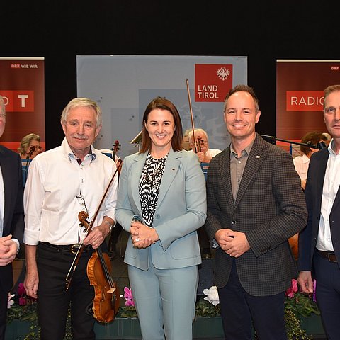 Vor einem Orchester in der Messe Innsbruck stehen von links Congress-Messe-Direktor Christian Mayerhofer, Wolfgang Niedermayr, Leiter des Salonorchesters Veldidena, LRin Astrid Mair, Markus Lassenberger, Vizebürgermeister Innsbruck, Franz Jirka, Wirtschaftskammer Tirol.