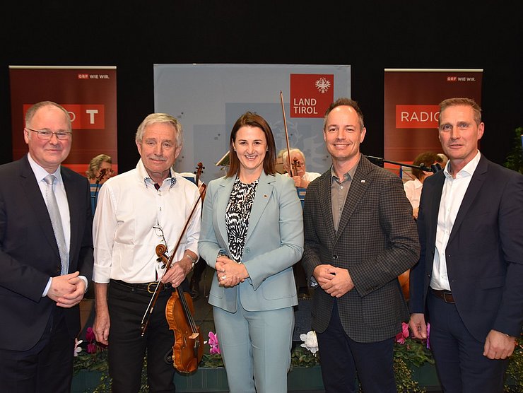 Vor einem Orchester in der Messe Innsbruck stehen von links Congress-Messe-Direktor Christian Mayerhofer, Wolfgang Niedermayr, Leiter des Salonorchesters Veldidena, LRin Astrid Mair, Markus Lassenberger, Vizebürgermeister Innsbruck, Franz Jirka, Wirtschaftskammer Tirol.