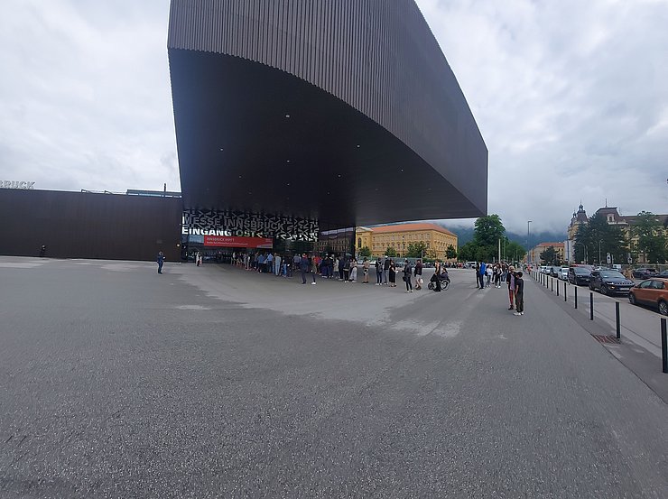 Messehalle in Innsbruck mit wartenden Menschen.