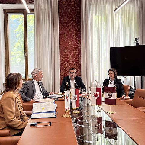 Landesrätin Astrid Mair (rechts), der Landeshauptmann von Trentino Maurizio Fugatti (mitte) und Landesrat Arno Schuler aus Südtirol sitzen an einem Tisch und präsentieren das neue Abkommen zur Zusammenarbeit im Zivil- und Katastrophenschutz.