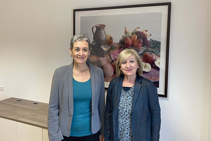 Kulturstaatssekretärin Ulrike Lunacek und Kulturlandesrätin Beate Palfrader stehen vor einem Gemälde im Staatssekretäriat. 