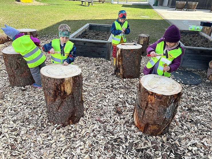 Kinder spielen mit Baumstämmen
