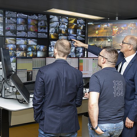 Foto von LH Mattle und Staatssekretär Florian Tursky vor vielen Bildschirmen im Gespräch mit einem Mitarbeiter der Leitstelle Tirol