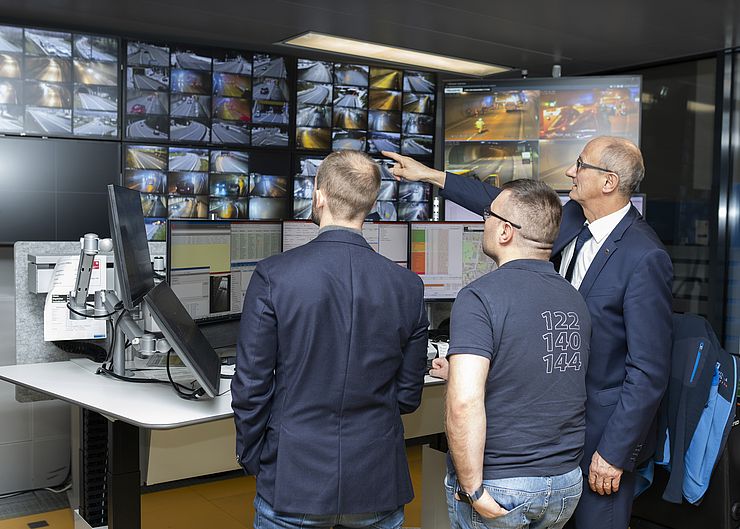 Foto von LH Mattle und Staatssekretär Florian Tursky vor vielen Bildschirmen im Gespräch mit einem Mitarbeiter der Leitstelle Tirol