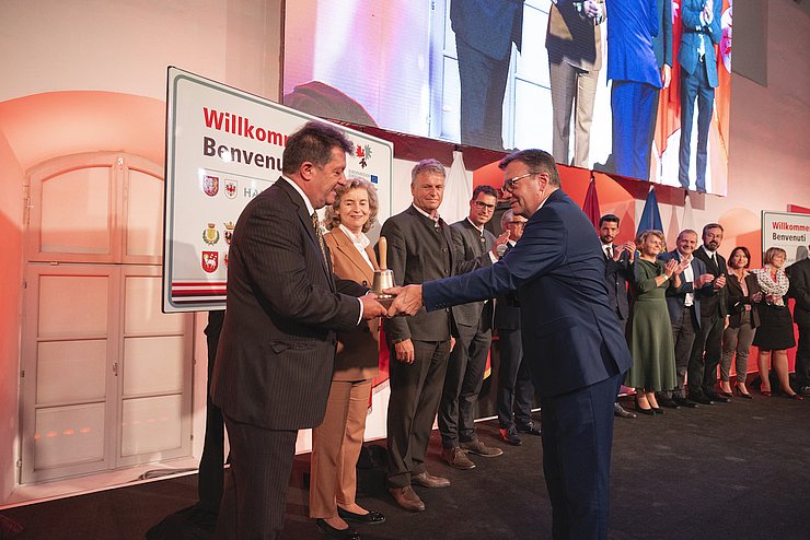 LH Platter überreicht die „Euregio-Sitzungsglocke“ an Gemeindeverbandspräsident Ernst Schöpf bei der Konstituierung des Euregio-Rats der Gemeinden. Im Bild die Mitglieder des Euregio-Rats der Gemeinden.