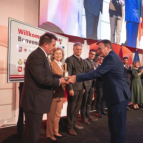 LH Platter überreicht die „Euregio-Sitzungsglocke“ an Gemeindeverbandspräsident Ernst Schöpf bei der Konstituierung des Euregio-Rats der Gemeinden. Im Bild die Mitglieder des Euregio-Rats der Gemeinden.